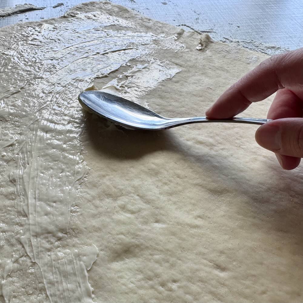 Ausgerollter Hefeteig für Bullar mit Margarine bestreichen